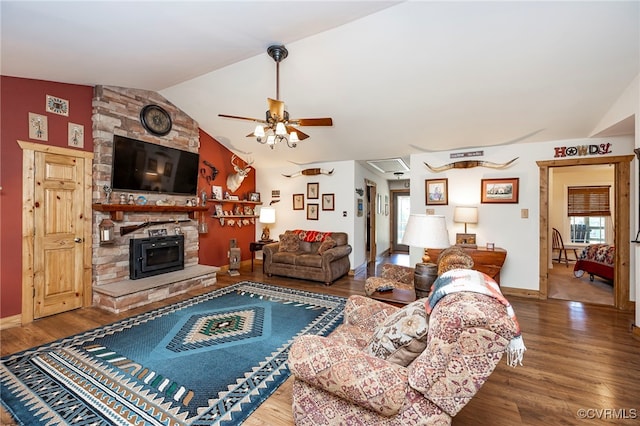 living room featuring a wood stove, ceiling fan, hardwood / wood-style floors, and vaulted ceiling