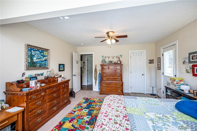 carpeted bedroom featuring ceiling fan and a textured ceiling