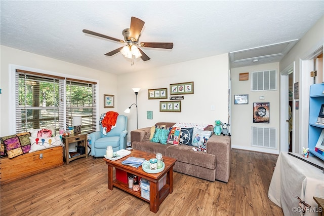 living room featuring a textured ceiling, light hardwood / wood-style flooring, and ceiling fan