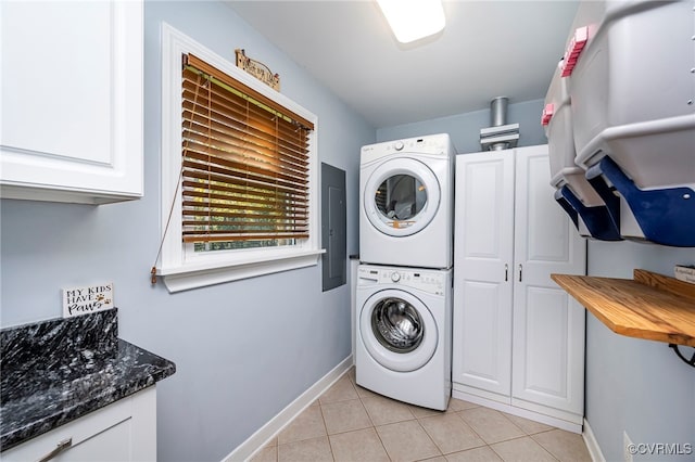 laundry area with cabinets, light tile patterned floors, stacked washer and dryer, and electric panel