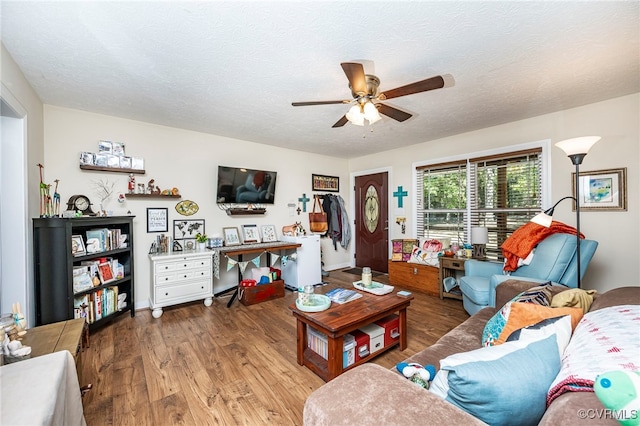 living room with ceiling fan, a textured ceiling, and hardwood / wood-style flooring