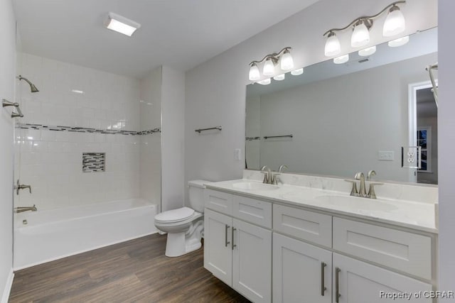 full bathroom featuring hardwood / wood-style floors, vanity, toilet, and tiled shower / bath