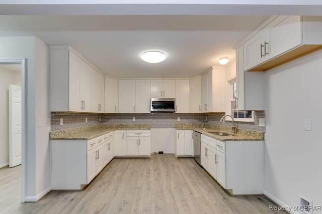 kitchen featuring white cabinets, stainless steel appliances, light stone counters, and sink