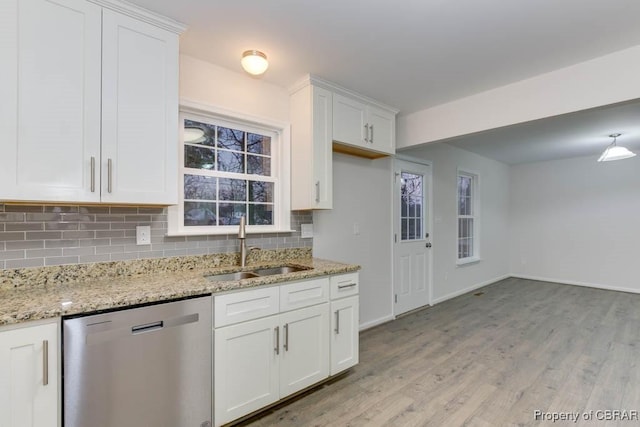 kitchen with decorative backsplash, light stone countertops, stainless steel dishwasher, sink, and white cabinets