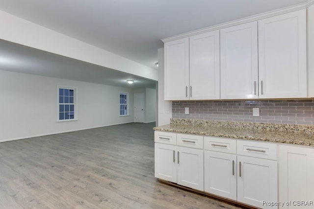 kitchen featuring decorative backsplash, white cabinetry, light hardwood / wood-style flooring, and light stone countertops