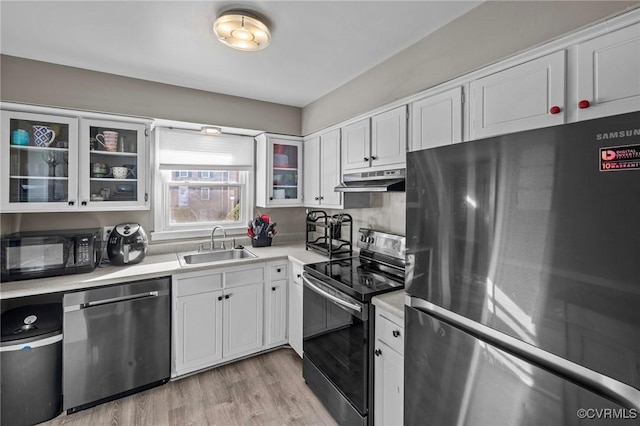 kitchen with stainless steel appliances, light hardwood / wood-style flooring, white cabinetry, and sink