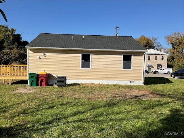 back of property with a deck, a yard, and central AC