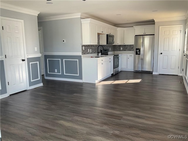 kitchen with appliances with stainless steel finishes, backsplash, dark wood-type flooring, crown molding, and white cabinets