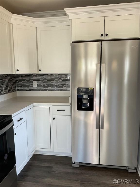 kitchen with tasteful backsplash, white cabinets, dark wood-type flooring, and appliances with stainless steel finishes