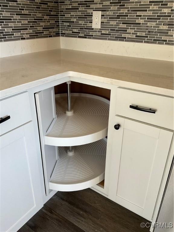 interior details featuring white cabinets, dark hardwood / wood-style floors, and tasteful backsplash