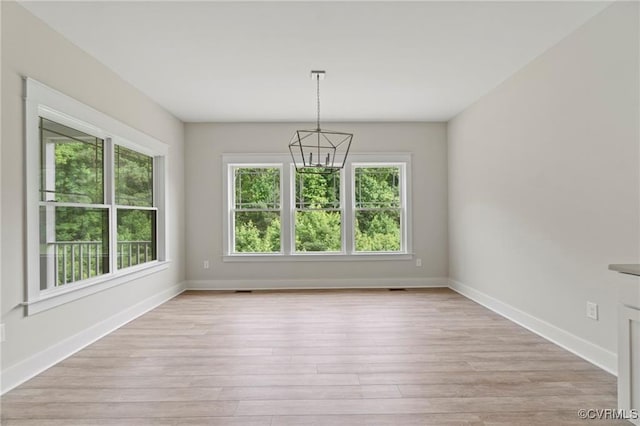 unfurnished dining area with light wood-type flooring and a notable chandelier