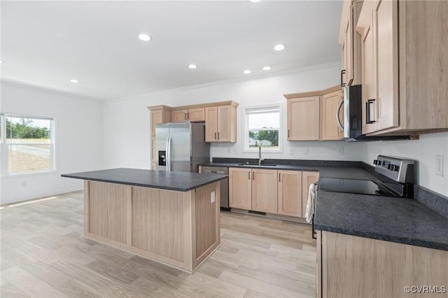 kitchen with light brown cabinetry, stainless steel appliances, a kitchen island, and sink