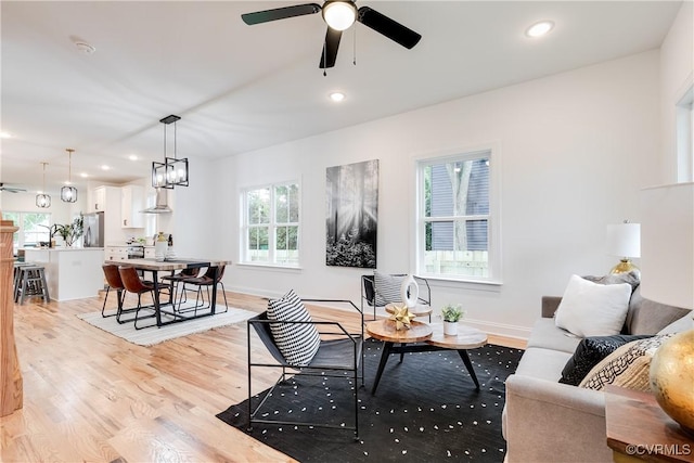 living room with light hardwood / wood-style flooring and ceiling fan with notable chandelier