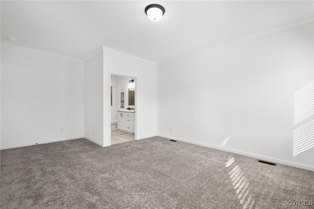 unfurnished bedroom featuring ensuite bath, light colored carpet, and ornamental molding