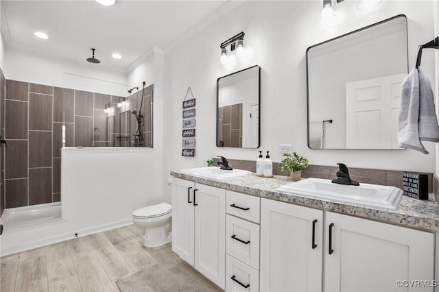 bathroom featuring vanity, crown molding, hardwood / wood-style flooring, toilet, and walk in shower