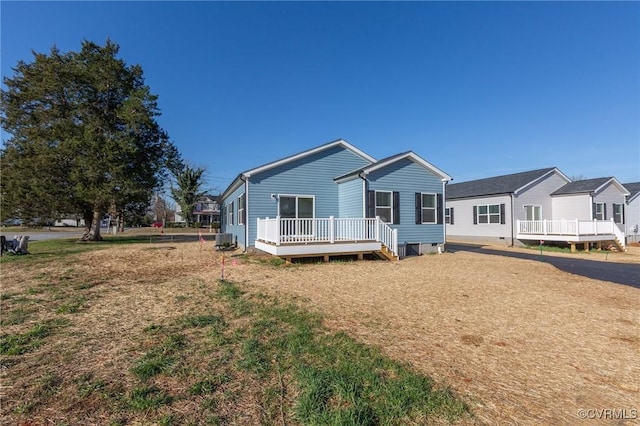 rear view of house featuring central AC, a deck, and a lawn