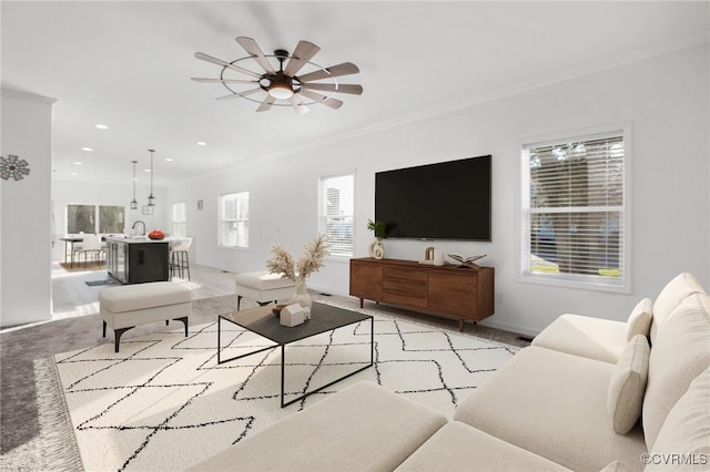 living room featuring a wealth of natural light, ceiling fan, sink, and ornamental molding