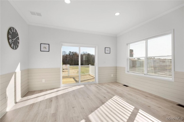 empty room featuring light wood-type flooring and ornamental molding