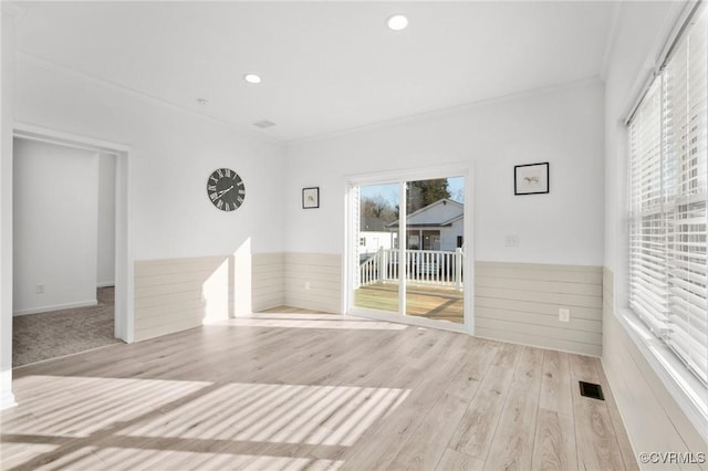 spare room featuring light wood-type flooring and ornamental molding