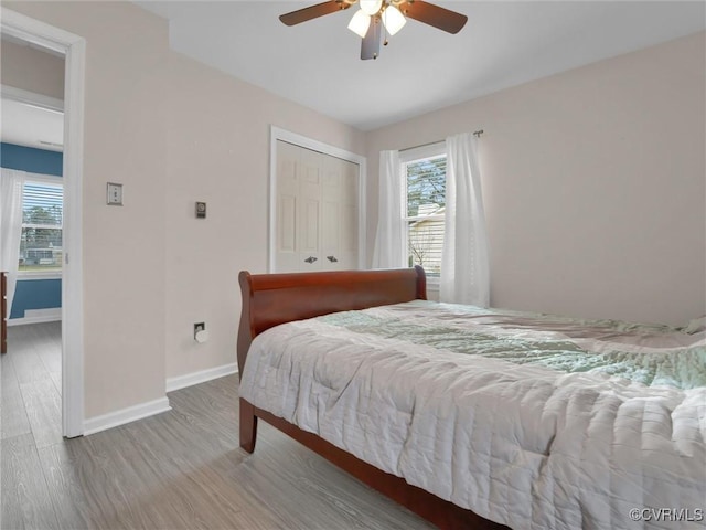 bedroom with baseboards, multiple windows, a closet, and wood finished floors