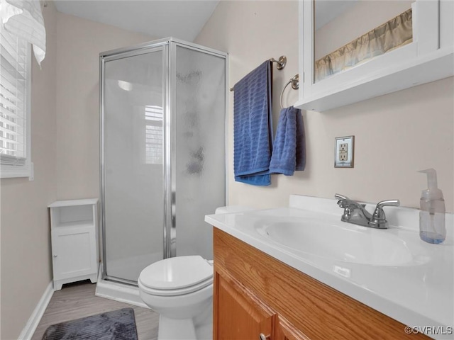 bathroom with wood finished floors, toilet, a stall shower, and vanity