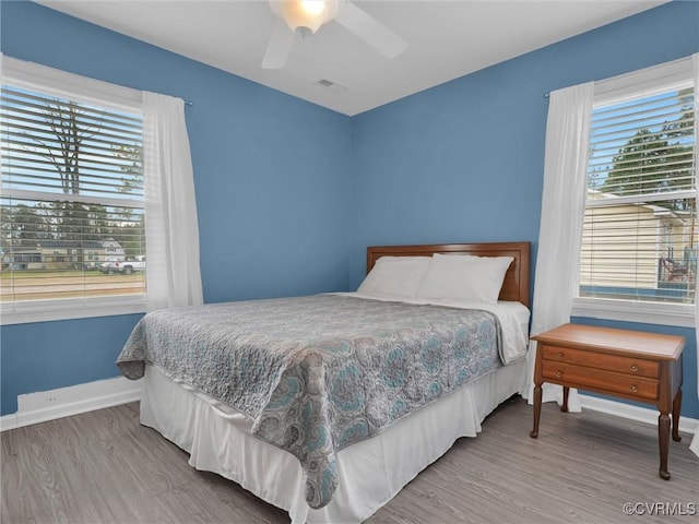 bedroom featuring visible vents, a ceiling fan, baseboards, and wood finished floors