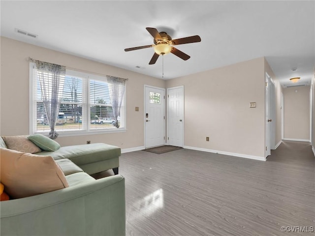 living area featuring visible vents, ceiling fan, baseboards, and wood finished floors