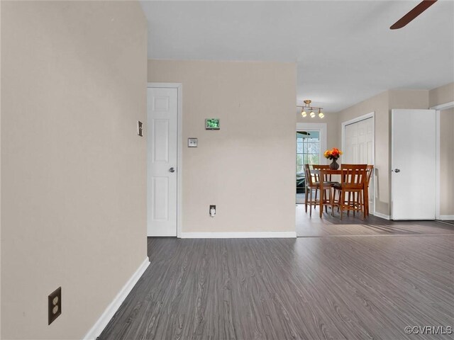 unfurnished room with baseboards, a ceiling fan, and dark wood-style flooring