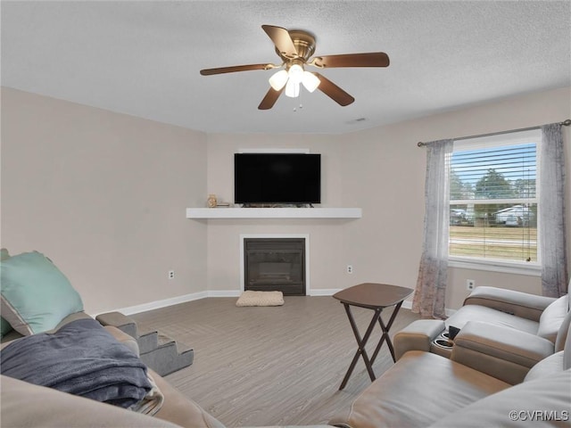 living room featuring ceiling fan, a textured ceiling, and hardwood / wood-style flooring