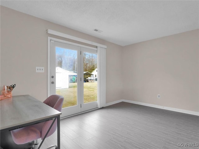 office space with visible vents, a textured ceiling, baseboards, and wood finished floors