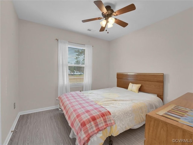 bedroom with visible vents, wood finished floors, baseboards, and ceiling fan