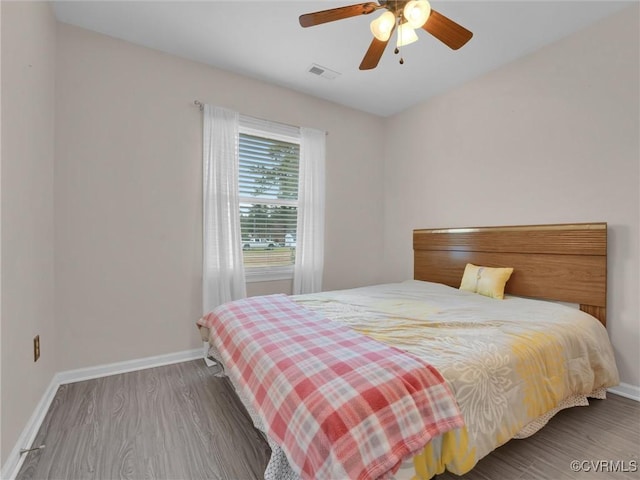 bedroom with visible vents, a ceiling fan, baseboards, and wood finished floors