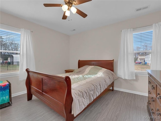 bedroom with ceiling fan, light hardwood / wood-style floors, and multiple windows