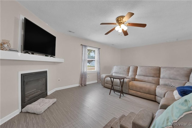 living room with ceiling fan, a textured ceiling, and wood-type flooring