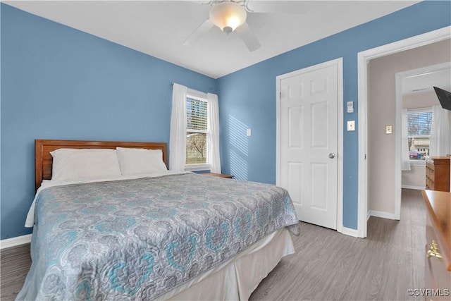 bedroom with a ceiling fan, baseboards, and wood finished floors