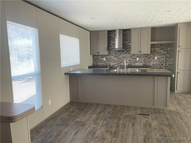 kitchen with sink, dark wood-type flooring, wall chimney range hood, a textured ceiling, and gray cabinets