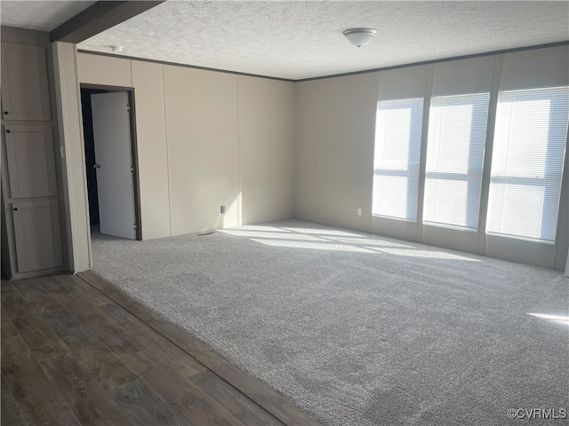 spare room featuring a textured ceiling and dark colored carpet