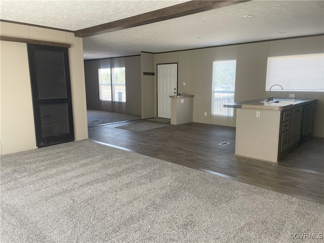 interior space with a textured ceiling, dark hardwood / wood-style flooring, sink, and beamed ceiling