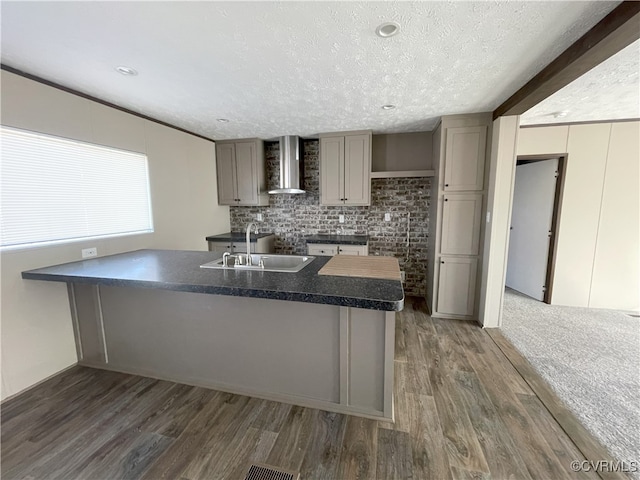 kitchen featuring gray cabinetry, wall chimney exhaust hood, a textured ceiling, dark wood-type flooring, and sink