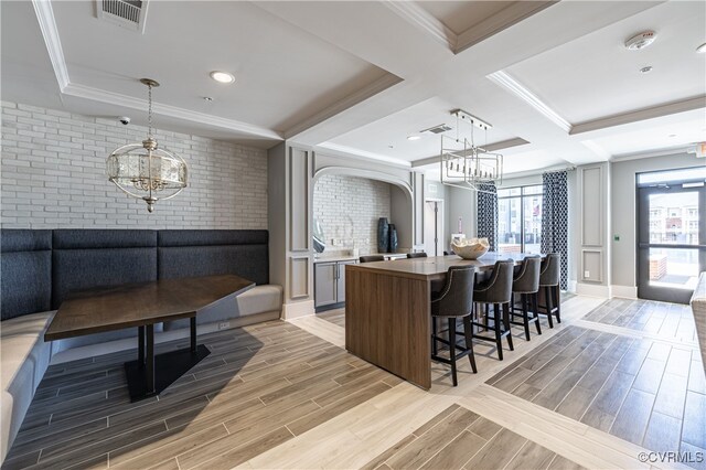 kitchen featuring decorative light fixtures, a kitchen island, ornamental molding, and coffered ceiling