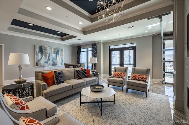 living room with a raised ceiling, french doors, a notable chandelier, and ornamental molding