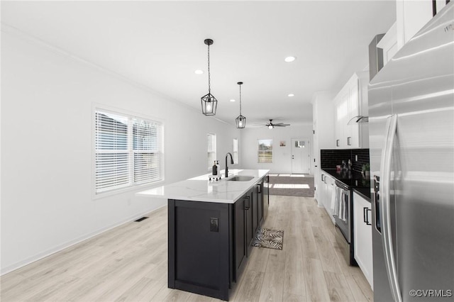 kitchen featuring pendant lighting, stainless steel appliances, white cabinetry, and a kitchen island with sink