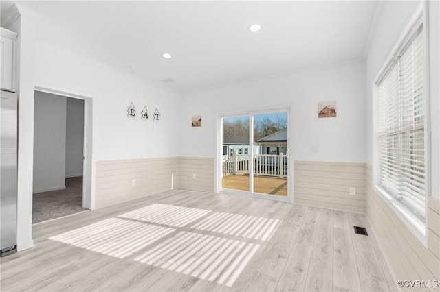 unfurnished room with ornamental molding, light wood-type flooring, and a healthy amount of sunlight