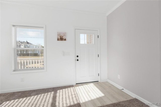 carpeted foyer entrance with ornamental molding and a healthy amount of sunlight