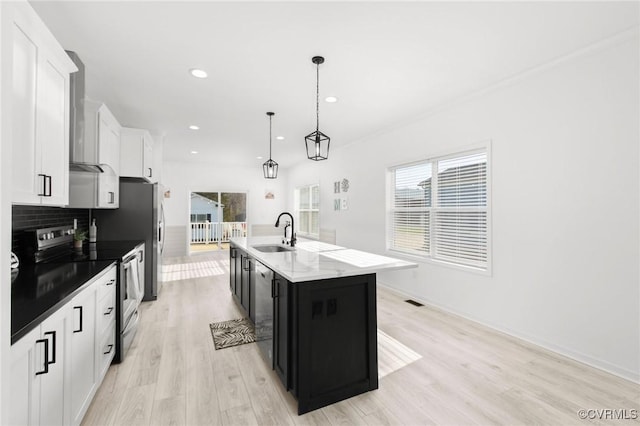 kitchen featuring a kitchen island with sink, white cabinets, sink, stainless steel electric range oven, and decorative light fixtures