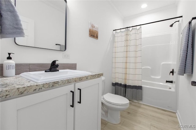 full bathroom featuring crown molding, hardwood / wood-style floors, toilet, shower / tub combo with curtain, and vanity