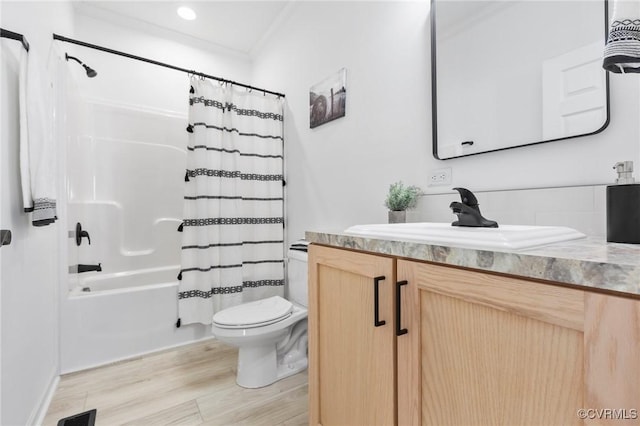 full bathroom featuring shower / bath combination with curtain, ornamental molding, vanity, hardwood / wood-style floors, and toilet