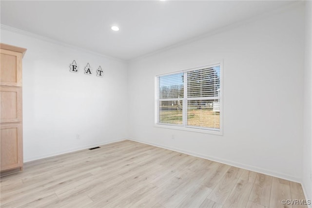 spare room with ornamental molding and light hardwood / wood-style flooring