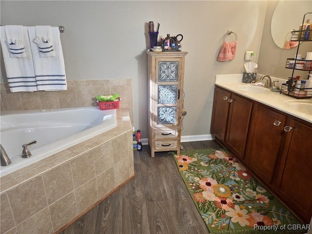 bathroom with vanity, a relaxing tiled tub, and hardwood / wood-style flooring