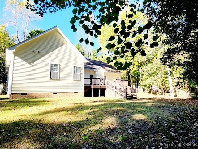 back of house featuring a lawn and a wooden deck